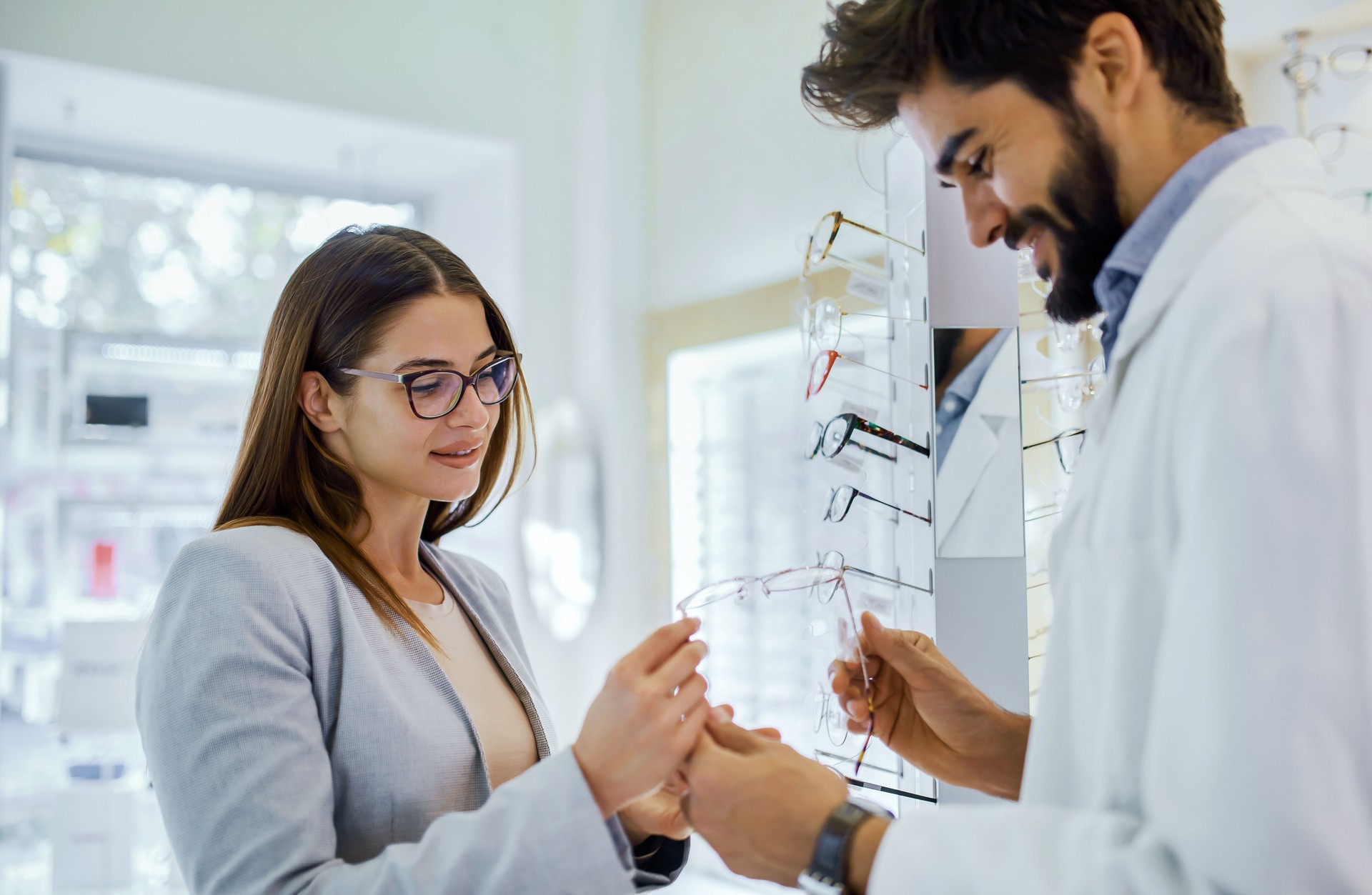 Customer tries on glasses while consulting with an eye care professional in a bright optical store